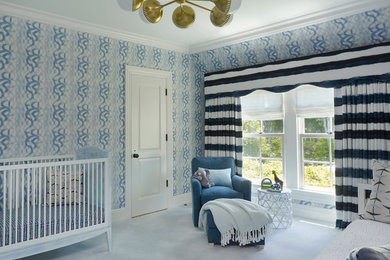 This is an example of a transitional nursery for boys in New York with blue walls, carpet and blue floor.