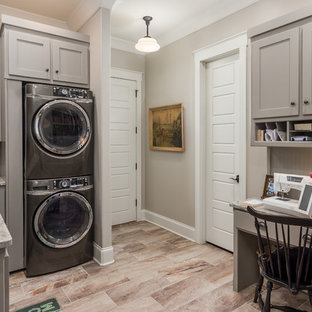 Design ideas for a medium sized country u-shaped separated utility room in Nashville with a submerged sink, recessed-panel cabinets, grey cabinets, granite worktops, a stacked washer and dryer and beige walls.
