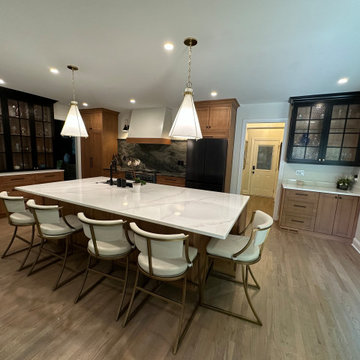 Large wood-base island with white countertop, plentiful seating and stylish pend