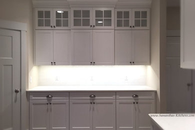 This is an example of a large classic single-wall kitchen/diner in Other with a submerged sink, shaker cabinets, white cabinets, engineered stone countertops, white splashback, metro tiled splashback, medium hardwood flooring and an island.