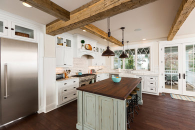 Large country l-shaped eat-in kitchen in Cincinnati with a farmhouse sink, white cabinets, white splashback, stainless steel appliances, dark hardwood floors, with island, marble benchtops, beaded inset cabinets, porcelain splashback and brown floor.