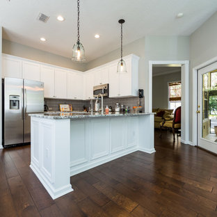 Large kitchen pantry appliance - Example of a large l-shaped dark wood floor kitchen pantry design in Jacksonville with a drop-in sink, recessed-panel cabinets, white cabinets, granite countertops, gray backsplash, subway tile backsplash and stainless steel appliances