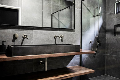 ゴールドコーストにあるおしゃれな浴室 (フラットパネル扉のキャビネット、グレーのタイル、グレーの壁、ベッセル式洗面器、木製洗面台) の写真
