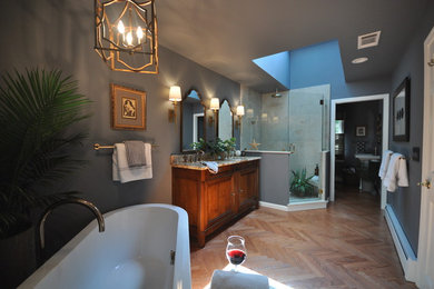 Example of a large eclectic master beige tile and porcelain tile medium tone wood floor and brown floor bathroom design in Bridgeport with an undermount sink, medium tone wood cabinets, granite countertops, gray walls, recessed-panel cabinets and a hinged shower door