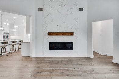 Diseño de salón abierto y abovedado moderno grande con paredes blancas, suelo de madera clara, chimenea lineal, marco de chimenea de metal y suelo marrón