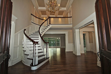 Foto de escalera curva clásica extra grande con escalones de madera, contrahuellas de madera pintada, barandilla de madera y boiserie