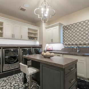 フェニックスのサンタフェスタイルのおしゃれな洗濯室 (アンダーカウンターシンク、落し込みパネル扉のキャビネット、ベージュのキャビネット、ベージュの壁、左右配置の洗濯機・乾燥機、マルチカラーの床、茶色いキッチンカウンター) の写真