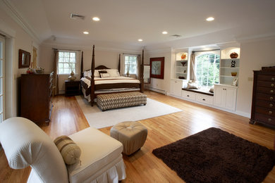 Traditional master bedroom in Boston with beige walls and light hardwood floors.