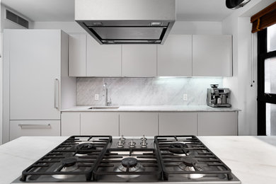 Example of a mid-sized trendy light wood floor kitchen design in New York with an undermount sink, flat-panel cabinets, gray cabinets, marble countertops, multicolored backsplash, marble backsplash, paneled appliances, an island and multicolored countertops