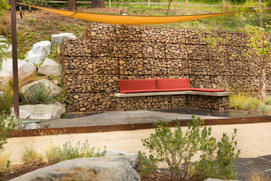This is an example of a large drought-tolerant and full sun front yard stone retaining wall landscape in Other.