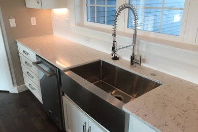 Kitchen - mid-sized transitional l-shaped dark wood floor and brown floor kitchen idea in Other with a farmhouse sink, shaker cabinets, white cabinets, quartz countertops, white backsplash, ceramic backsplash, stainless steel appliances, an island and white countertops