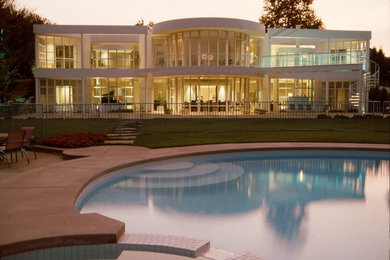 This is an example of a large modern two-storey glass white house exterior in Orange County with a flat roof.