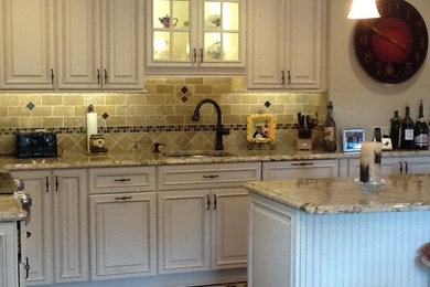 Inspiration for a large timeless l-shaped medium tone wood floor open concept kitchen remodel in New York with raised-panel cabinets, granite countertops, brown backsplash, stainless steel appliances, an island, an undermount sink, stone tile backsplash and white cabinets