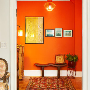 Foto de distribuidor ecléctico, pequeño, con parades naranjas, suelo de madera clara, puerta simple y puerta blanca