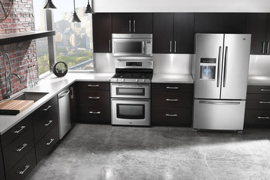 This is an example of a large transitional l-shaped separate kitchen in New York with a drop-in sink, dark wood cabinets, stainless steel appliances and flat-panel cabinets.