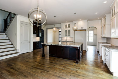 Photo of a large transitional l-shaped open plan kitchen in Atlanta with a farmhouse sink, granite benchtops, white splashback, medium hardwood floors and with island.