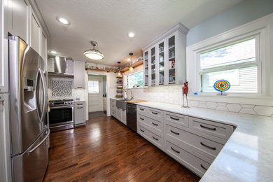 Mid-sized transitional u-shaped medium tone wood floor and brown floor enclosed kitchen photo in Kansas City with a farmhouse sink, shaker cabinets, gray cabinets, quartzite countertops, white backsplash, porcelain backsplash, stainless steel appliances, no island and white countertops