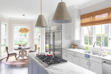 Inspiration for a large traditional l-shaped eat-in kitchen in Houston with an undermount sink, recessed-panel cabinets, white cabinets, quartzite benchtops, white splashback, ceramic splashback, stainless steel appliances, dark hardwood floors, multiple islands, brown floor and white benchtop.