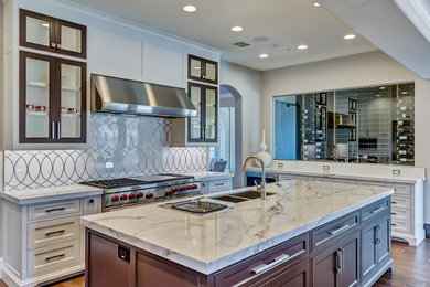 Inspiration for an expansive transitional u-shaped open plan kitchen in Orange County with an undermount sink, shaker cabinets, white cabinets, marble benchtops, white splashback, marble splashback, stainless steel appliances, multiple islands, brown floor and porcelain floors.
