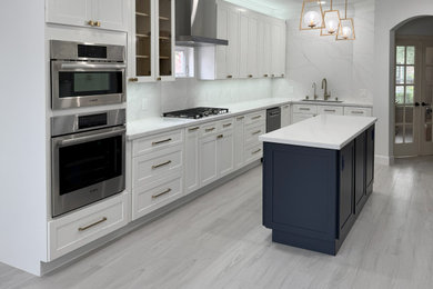 Example of a mid-sized transitional u-shaped porcelain tile and gray floor eat-in kitchen design in Houston with an undermount sink, shaker cabinets, blue cabinets, quartz countertops, white backsplash, quartz backsplash, stainless steel appliances, an island and white countertops