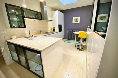 Réalisation d'une grande cuisine design en L fermée avec un évier encastré, un placard à porte affleurante, des portes de placard blanches, un plan de travail en calcaire, une crédence beige, une crédence en pierre calcaire, un électroménager noir, un sol en marbre, aucun îlot, un sol beige et un plan de travail beige.