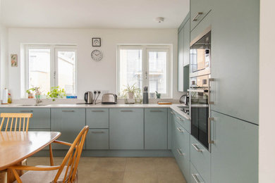 Medium sized l-shaped kitchen/diner in Cornwall with a submerged sink, flat-panel cabinets, green cabinets, quartz worktops, stainless steel appliances and grey worktops.