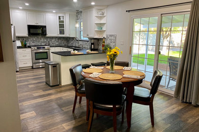 Example of a small trendy laminate floor and brown floor kitchen/dining room combo design in Phoenix with white walls and no fireplace