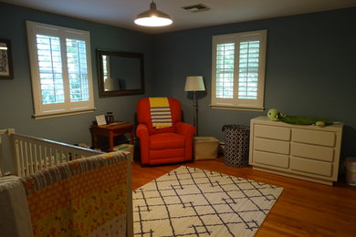Mid-sized traditional gender-neutral nursery in Other with blue walls and light hardwood floors.
