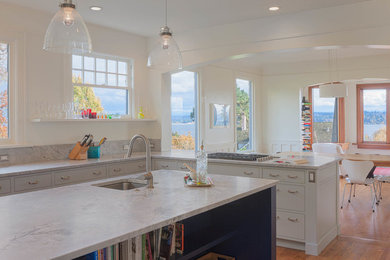 Large trendy l-shaped medium tone wood floor eat-in kitchen photo in Seattle with an undermount sink, beaded inset cabinets, white cabinets, marble countertops, stone slab backsplash, stainless steel appliances and an island