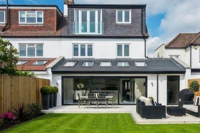 Design ideas for a large and white modern render semi-detached house in London with three floors, a hip roof, a tiled roof and a black roof.