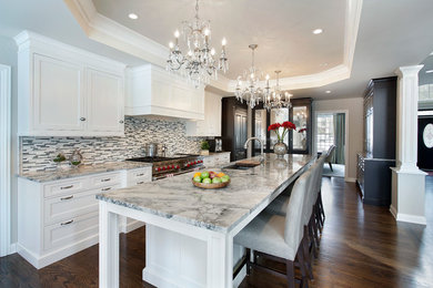 Example of a large classic l-shaped medium tone wood floor eat-in kitchen design in Chicago with an undermount sink, recessed-panel cabinets, white cabinets, quartzite countertops, gray backsplash, glass tile backsplash, paneled appliances and an island