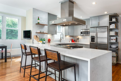 Design ideas for a mid-sized transitional u-shaped open plan kitchen in DC Metro with an undermount sink, recessed-panel cabinets, grey cabinets, quartz benchtops, white splashback, stainless steel appliances, medium hardwood floors, a peninsula, brown floor, subway tile splashback and white benchtop.