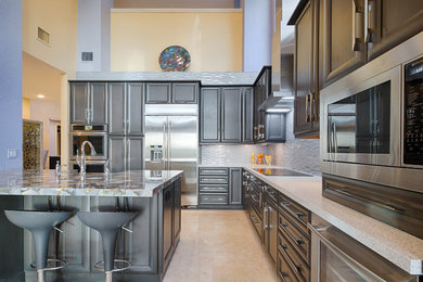 Trendy l-shaped beige floor kitchen photo in Philadelphia with a farmhouse sink, recessed-panel cabinets, dark wood cabinets, gray backsplash, stainless steel appliances, an island and white countertops