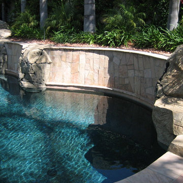 Pool and patio with stone / rock walls and deck