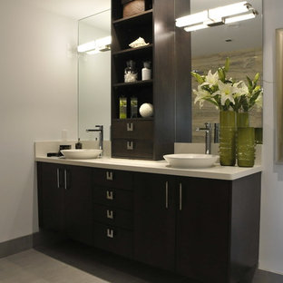 Idée de décoration pour une salle de bain principale design de taille moyenne avec un mur blanc, un placard à porte plane, des portes de placard en bois sombre, un WC suspendu, des carreaux de miroir, un sol en carrelage de céramique, une vasque, un plan de toilette en stratifié et un sol gris.