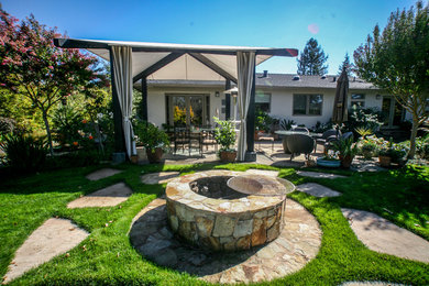 Photo of a large traditional backyard patio in San Francisco with a fire feature, natural stone pavers and an awning.