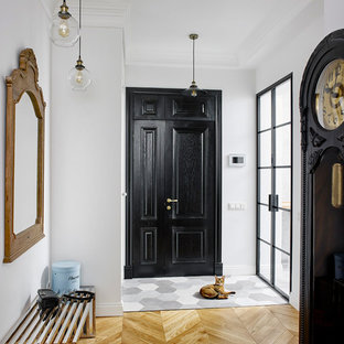 Diseño de puerta principal bohemia con paredes blancas, suelo de madera clara, puerta negra y puerta simple