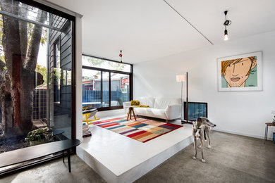 Contemporary open concept living room in Perth with white walls and concrete floors.