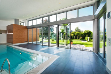 Mid-sized contemporary indoor rectangular pool in Other with tile.