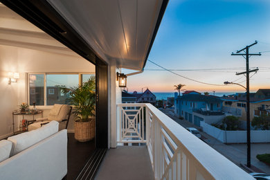 Beach style balcony in Los Angeles with a roof extension and wood railing.
