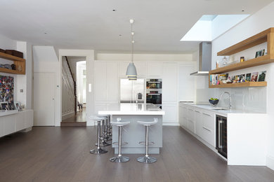 Design ideas for a contemporary l-shaped kitchen in London with an undermount sink, flat-panel cabinets, white cabinets, white splashback, glass sheet splashback, stainless steel appliances, medium hardwood floors and with island.