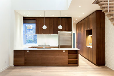 Mid-sized modern l-shaped kitchen in New York with flat-panel cabinets, dark wood cabinets, medium hardwood floors, stainless steel appliances and a peninsula.