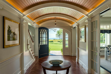 Example of a mid-sized beach style brown floor, wood ceiling, exposed beam, vaulted ceiling, wainscoting and medium tone wood floor entryway design in Portland Maine with a blue front door and gray walls