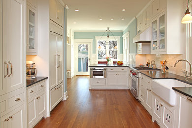 Elegant u-shaped kitchen photo in Minneapolis with a farmhouse sink, shaker cabinets, white cabinets, white backsplash, subway tile backsplash and paneled appliances