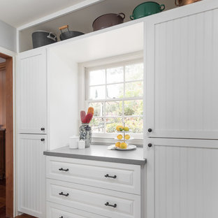 Bild på ett mellanstort maritimt grå grått kök, med en enkel diskho, luckor med profilerade fronter, vita skåp, bänkskiva i kvarts, flerfärgad stänkskydd, stänkskydd i terrakottakakel, rostfria vitvaror, mellanmörkt trägolv och brunt golv