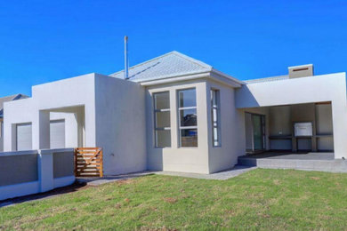 Example of a mid-sized transitional beige one-story house exterior design in Other with a hip roof, a tile roof and a gray roof