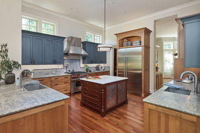 Large traditional open plan kitchen in Portland with a farmhouse sink, recessed-panel cabinets, medium wood cabinets, granite benchtops, blue splashback, ceramic splashback, stainless steel appliances, medium hardwood floors, with island and beige benchtop.