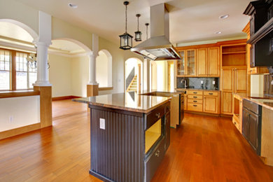 Open concept kitchen - large traditional l-shaped open concept kitchen idea in Seattle with raised-panel cabinets, medium tone wood cabinets, granite countertops, black backsplash, stone slab backsplash and an island