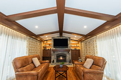 Mid-sized elegant open concept medium tone wood floor and brown floor family room photo in Other with brown walls, a standard fireplace, a stone fireplace and a wall-mounted tv