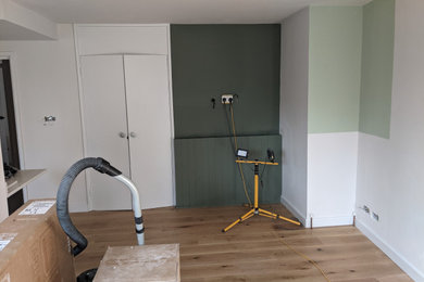 Photo of a medium sized scandinavian open plan living room feature wall in London with multi-coloured walls, medium hardwood flooring and a wall mounted tv.